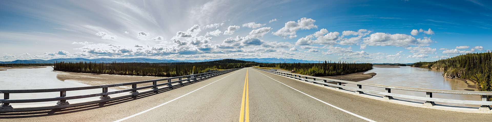The Alaska Highway running empty toward distant peaks