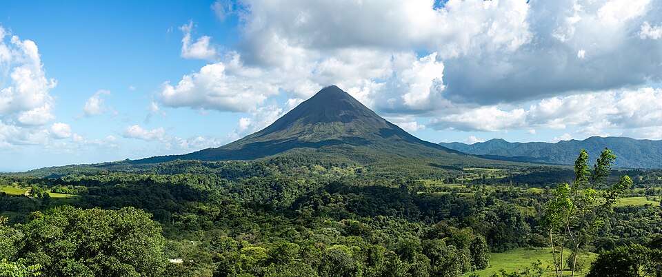 Arenal volcano's cone rising over rainforest