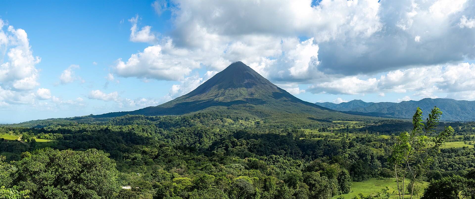 Arenal volcano's cone rising over rainforest