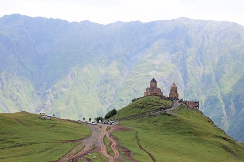 Gergeti Trinity Church alone on its ridge above Stepantsminda, the Caucasus wall behind it