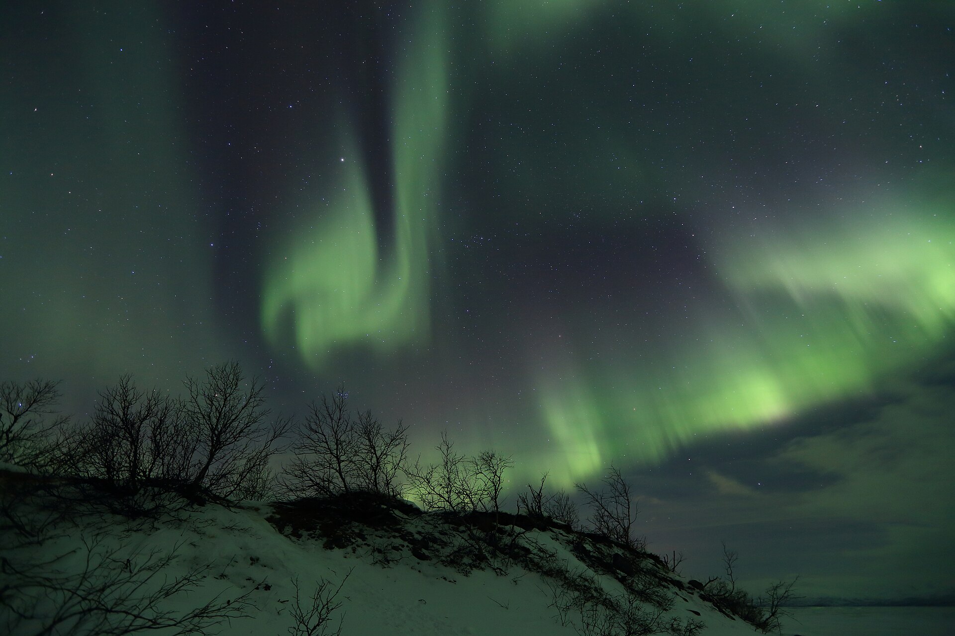 The aurora curling green over Abisko's frozen lake