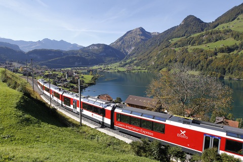 The Luzern–Interlaken Express beside Lake Lungern and snow-dusted peaks
